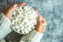 Overhead view of a woman holding a mug filled with mini marshmallows — Stock Photo