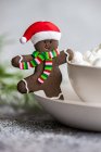 Weihnachten Lebkuchenmann im Weihnachtsmannhut neben einer Tasse Mini-Marshmallows — Stockfoto