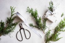Overhead view of a wrapped christmas gift with rustic thuja foliage decoration next to a candle — Stock Photo