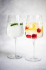 Two glasses of ice water with cucumber and raspberries with lemon — Stock Photo