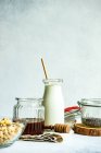 Cuenco de cereal junto a una botella de leche, semillas de chía y miel - foto de stock