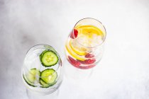 Two glasses of ice water with cucumber and raspberries with lemon — Stock Photo