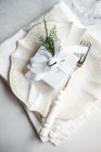 Overhead view of a wrapped Christmas gift on a formal place setting on a table — Stock Photo