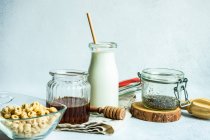 Schüssel Müsli neben einer Flasche Milch, Chiasamen und Honig — Stockfoto