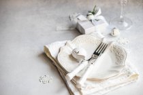 Overhead view of a wrapped Christmas gift and formal place setting on a table — Stock Photo