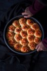 Vue aérienne d'une personne tenant une plaque de cuisson remplie de petits pains fraîchement cuits — Photo de stock