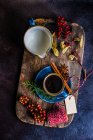 Café épicé de Noël dans une tasse en céramique bleue parmi les épices et les baies sur fond sombre et humide — Photo de stock