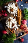 Tazas llenas de mini malvaviscos con especias sobre fondo oscuro como concepto de comida navideña - foto de stock