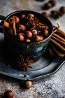 Weihnachtliches Essenskonzept mit Vintage-Becher voller Nüsse, Zimtstangen und Anis-Stern auf Betongrund — Stockfoto