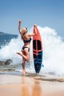 Giovane donna surfista sulla spiaggia soleggiata — Foto stock