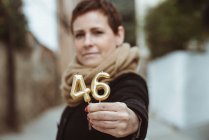 Middle aged woman holding 46 numbers candles — Stock Photo