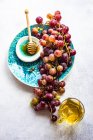 Top view of bunch of red grapes on plate with bowl of honey — Stock Photo