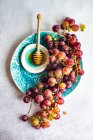 Vue du dessus du bouquet de raisins rouges sur assiette avec bol de miel — Photo de stock