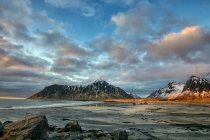 Rocky beach scene with mountains, Stor Sandnes, Flakstad, Lofoten, Nordland, Noruega - foto de stock