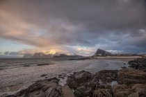 Cena de praia rochosa com montanhas ao pôr do sol, Stor Sandnes, Flakstad, Lofoten, Nordland, Noruega — Fotografia de Stock