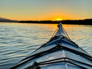 Каяк пливе по воді до берегової лінії на заході сонця (Канада). — стокове фото