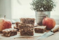 Homemade caramel blondie bars on wooden table with knife, apples and potted plant — Stock Photo