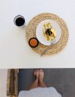 Pov знімок жіночих ніг поруч зі столом з чашкою кави та веганським шоколадом, ананасовий торт — стокове фото
