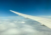 View through window of aircraft wing flying above clouds — Stock Photo