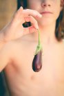 Close-up of a shirtless teenage boy holding a baby aubergine — Stock Photo