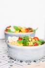 Dos tazones de ensalada con maíz dulce, tomate, arroz, cilantro y huevo de codorniz - foto de stock