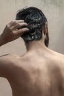 Visão traseira de um homem em pé no chuveiro lavar o cabelo — Fotografia de Stock