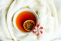 Вид сверху на чашку чая с ломтиком лимона, вязаный свитер и снежинку — стоковое фото