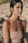 Woman with cream on her face wearing a bandeau top sitting on beach, Majorca, Spain — Stock Photo