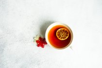 Tasse Tee mit getrockneten Orangenscheiben und Schneeflocken Dekoration auf dem Tisch — Stockfoto