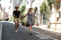 Усміхнена пара, що тримається за руки, йде по вулиці, Кареннак, Кверсі, Лот, Окситанія, Франція. — стокове фото