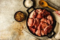Blick von oben auf frisches Schweinefleisch mit Schalen mit Chiliflocken und Meersalz — Stockfoto