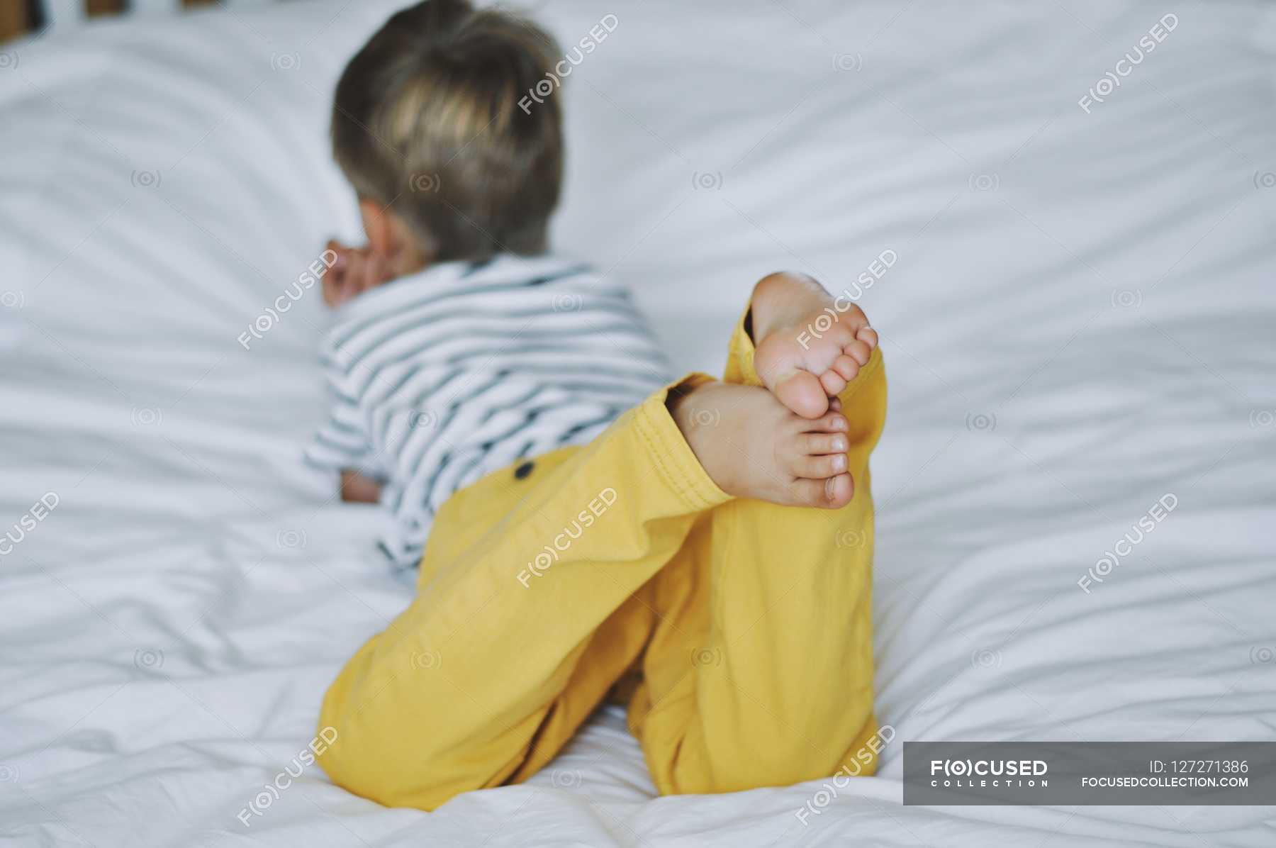 Мальчик лежит на кровати — Белый цвет, Barerfoot - Stock Photo | #127271386
