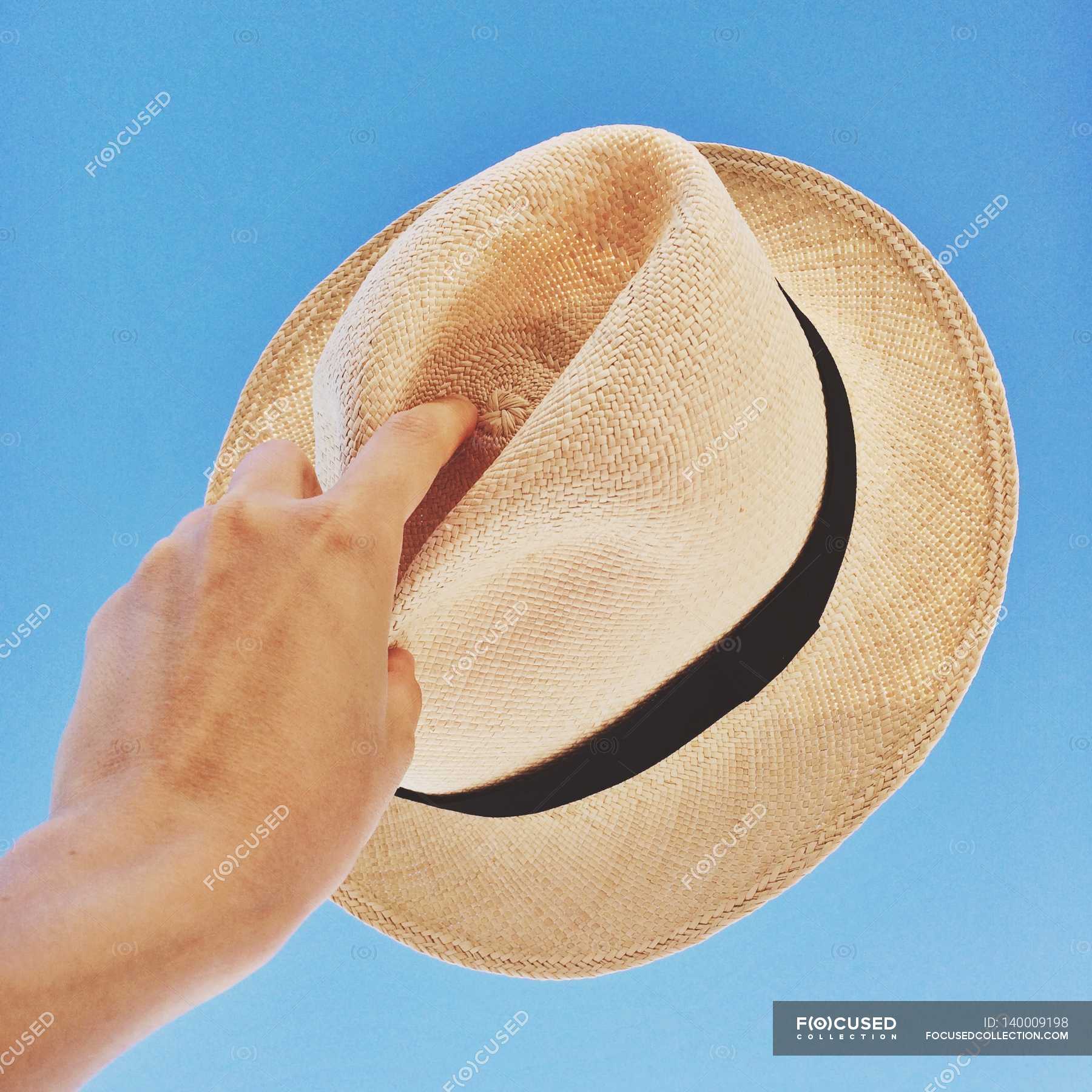 hand-holding-hat-up-to-sky-human-unrecognizable-person-stock-photo