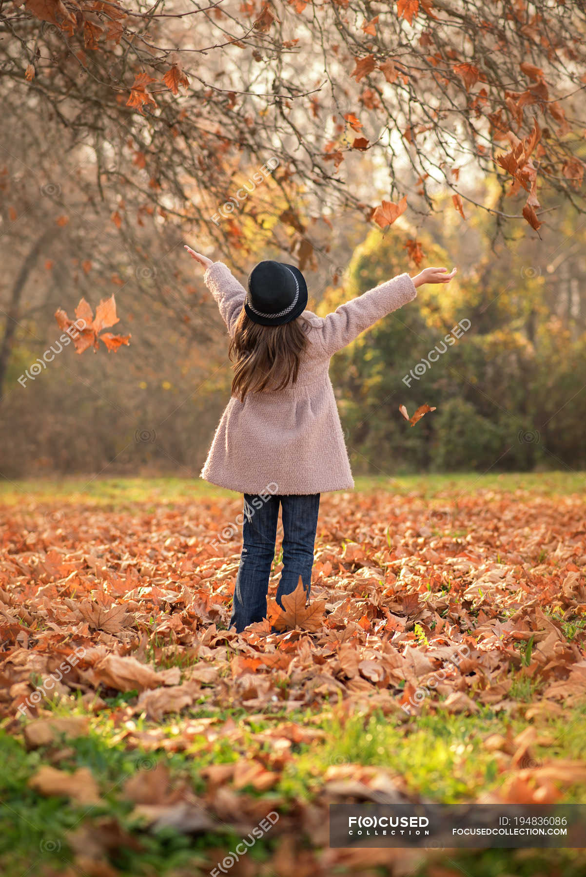 Девушка кидает осенние листья