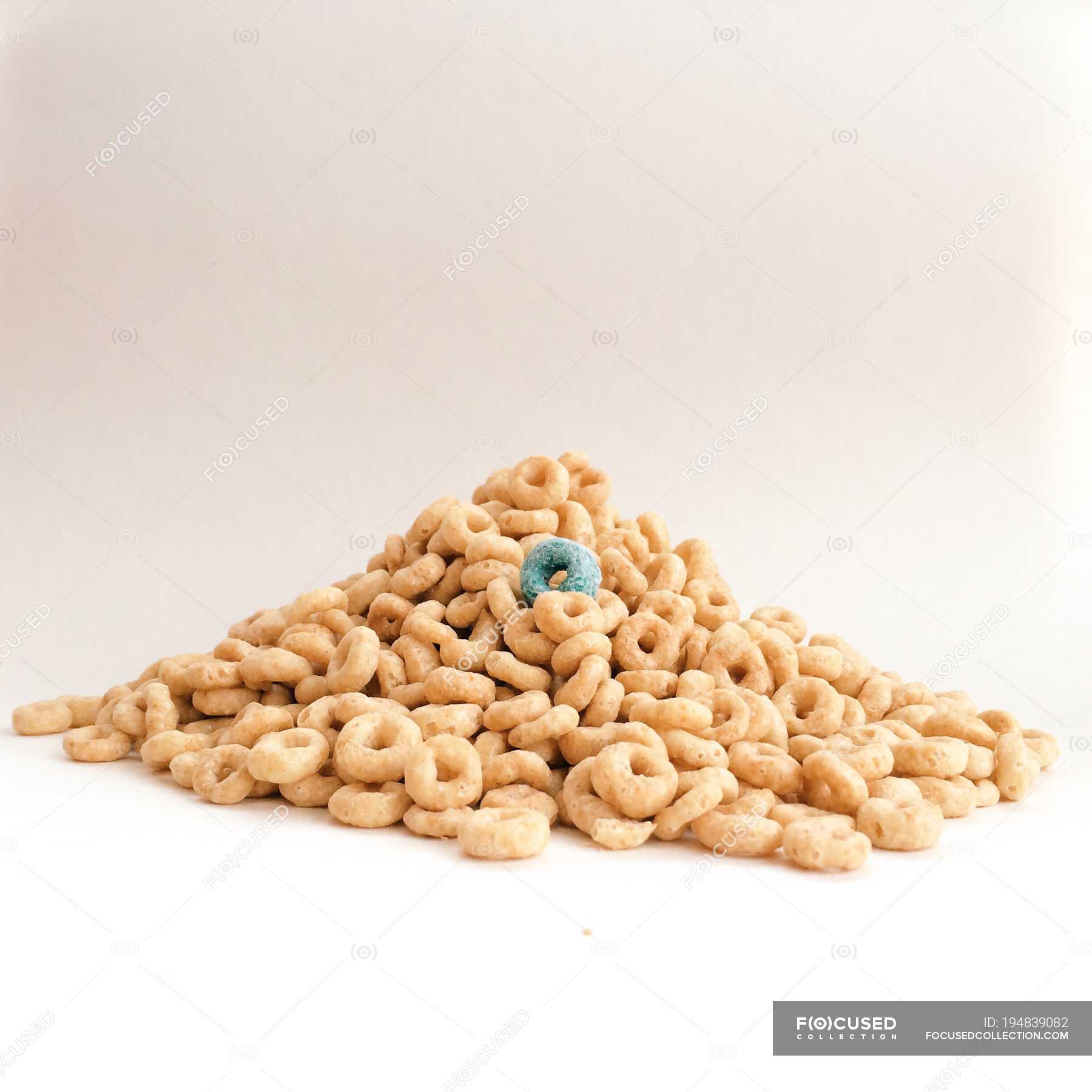 Pile of cereals with one blue cereal against white background — tasty