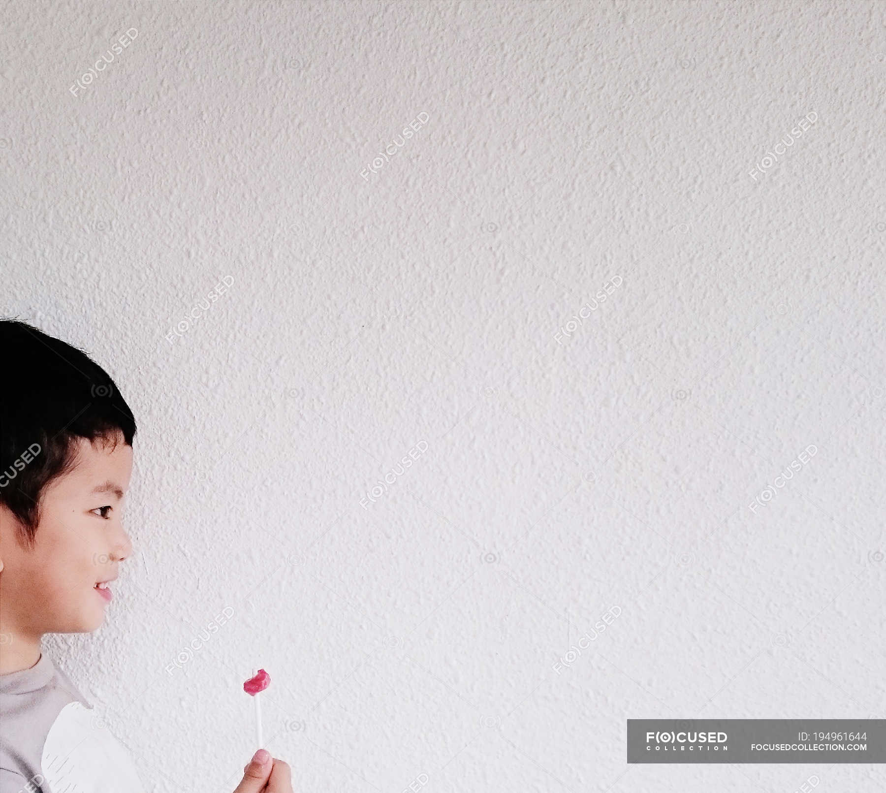 Smiling Boy Holding Half Eaten Lollipop In Front Of White Wall Profile Happiness Stock Photo