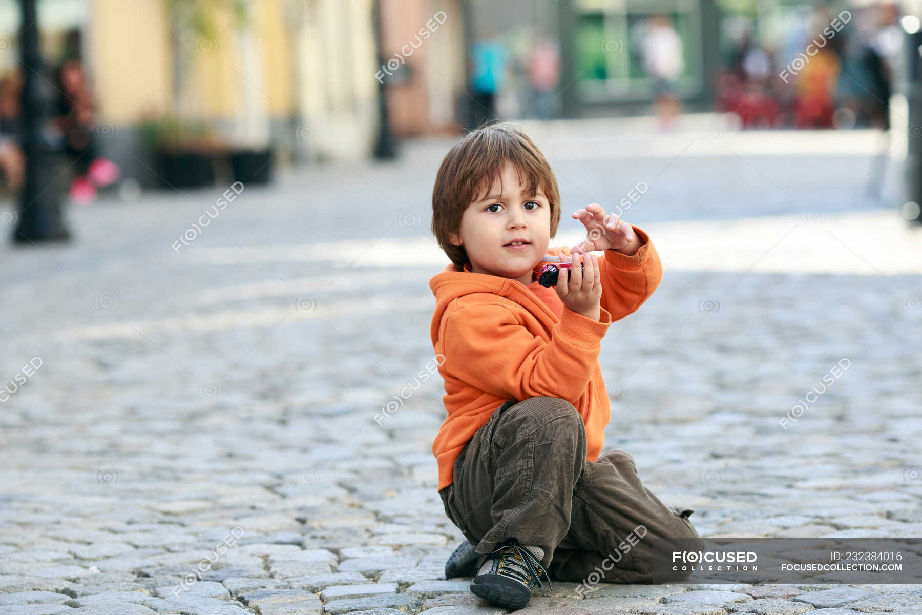 Boy sitting in street playing with toy car — child, city - Stock Photo ...