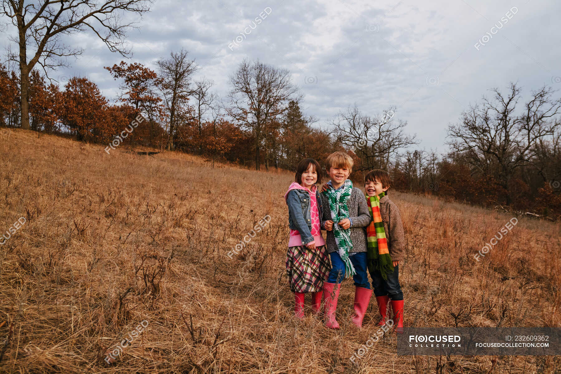 Portrait of three children standing in rural landscape — horizontal ...