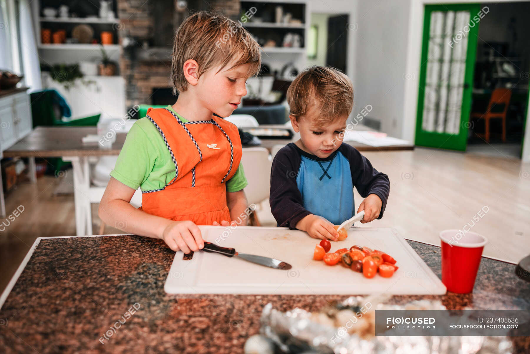 Zwei kleine Kinder helfen beim Kochen in der Küche — das Hinaushelfen