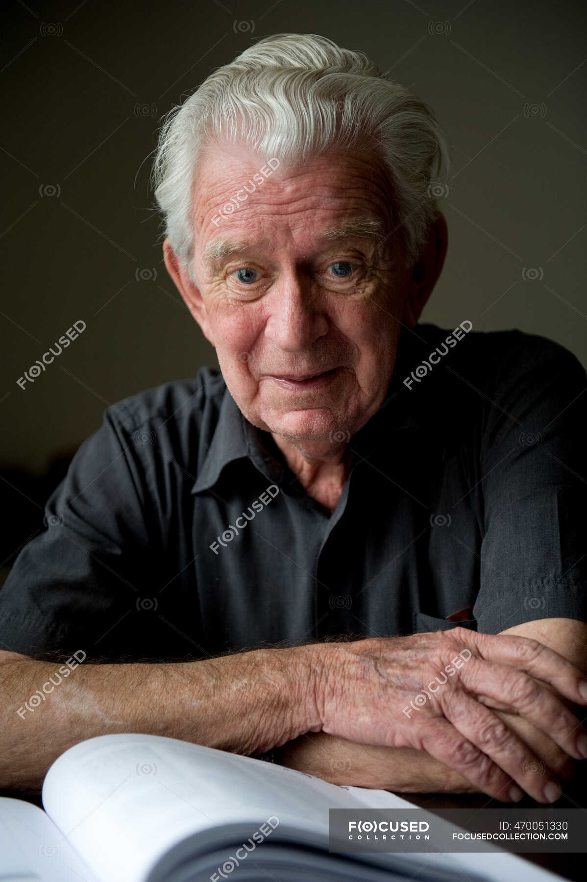 Portrait Of A Senior Man Sitting At A Table With A Book In Front Of Him