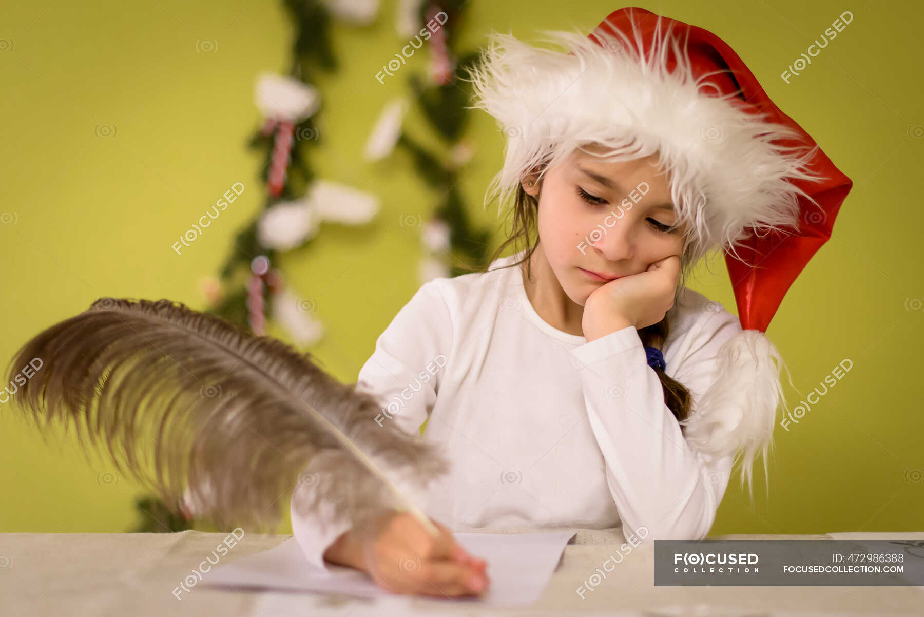 girl-wearing-a-santa-hat-writing-a-letter-to-santa-with-an-ostrich