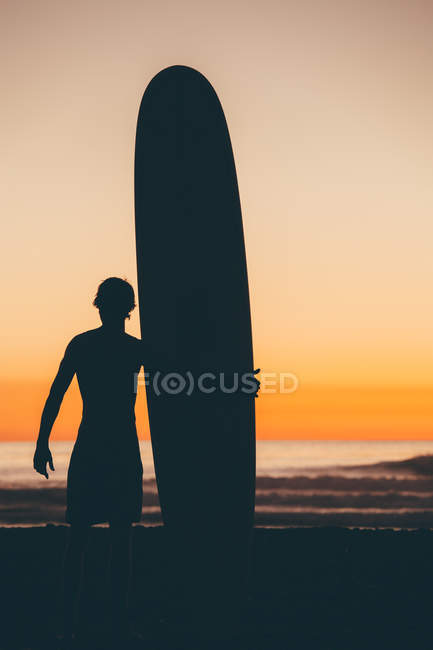 Surfeur debout sur la plage avec planche de surf — Photo de stock