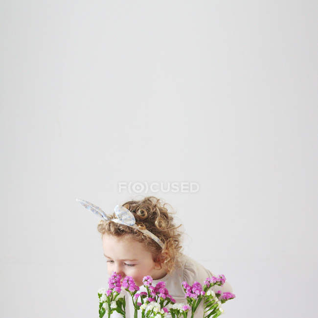 Mädchen in Hasenohren, die Blumen riechen — Stockfoto
