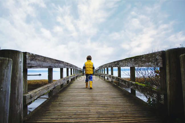 Хлопчик йде дерев'яним мостом — стокове фото