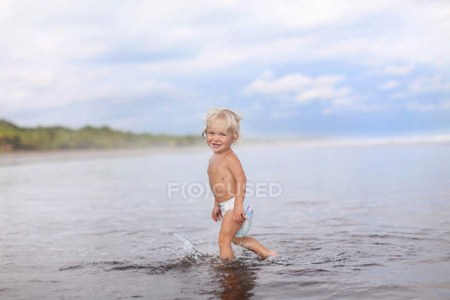 Niño caminando en agua de mar - foto de stock