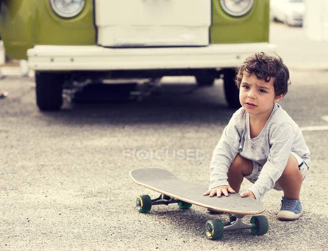 Child crouching with skateboard — Stock Photo
