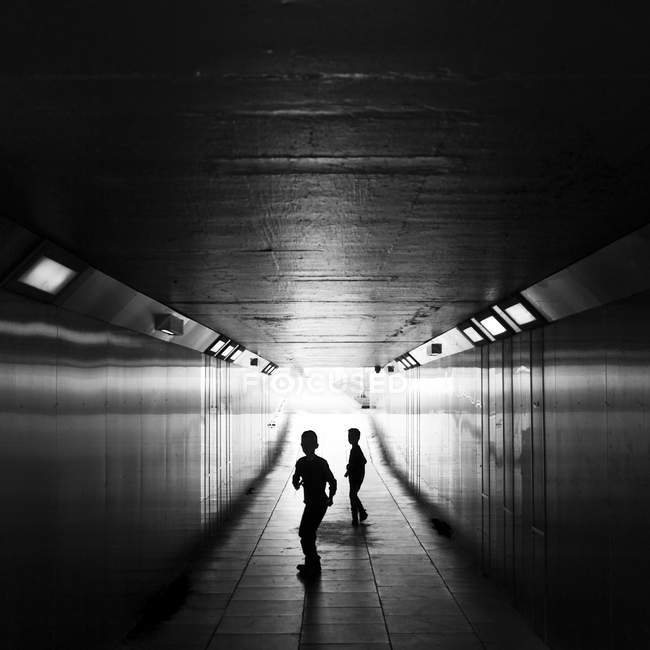 Silhouettes of children running in underpass — Stock Photo