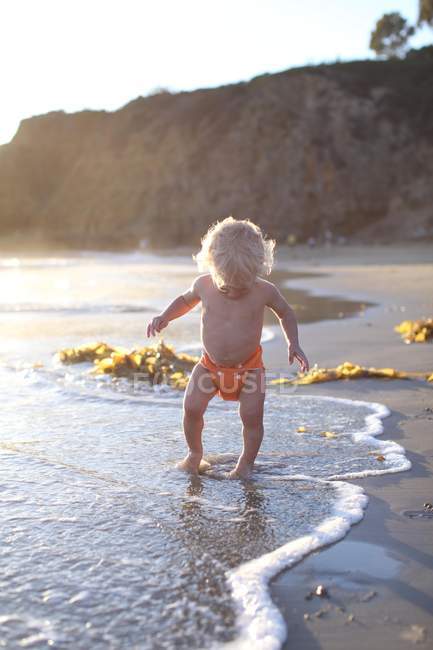 Niño pequeño caminando en la playa - foto de stock