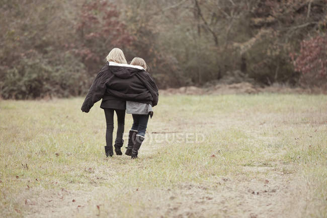 Sorelle che camminano insieme sul campo — Foto stock