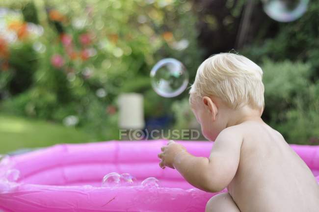 Toddler by pool with bubbles in air — Stock Photo